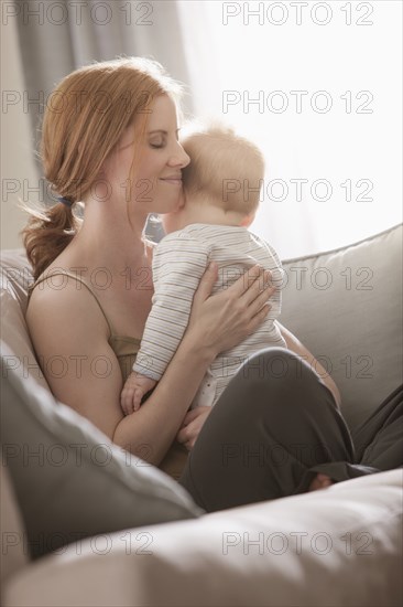 Caucasian mother sitting on sofa holding son