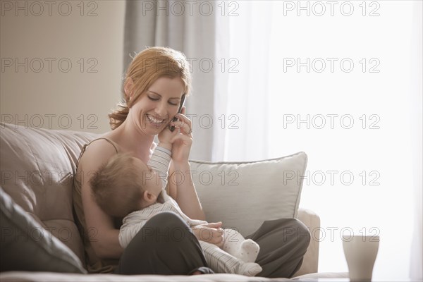 Caucasian mother holding son and talking on cell phone