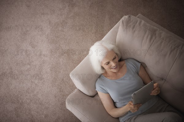 Caucasian woman using digital tablet on sofa