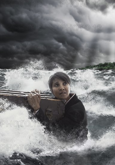 Mixed race woman clinging to trunk in stormy sea