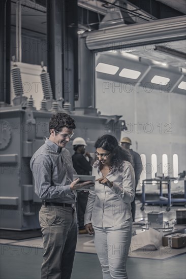 Workers using digital tablet together in factory