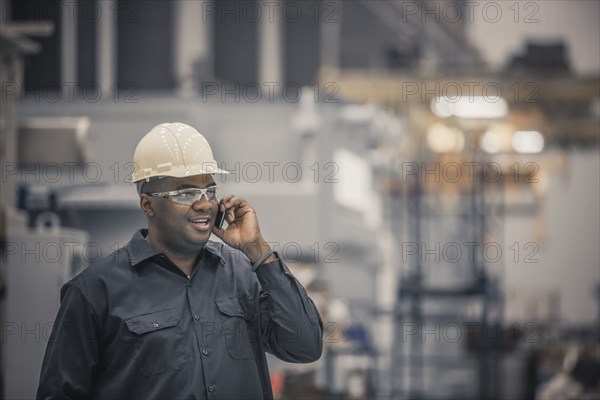 African American worker using cell phone in factory