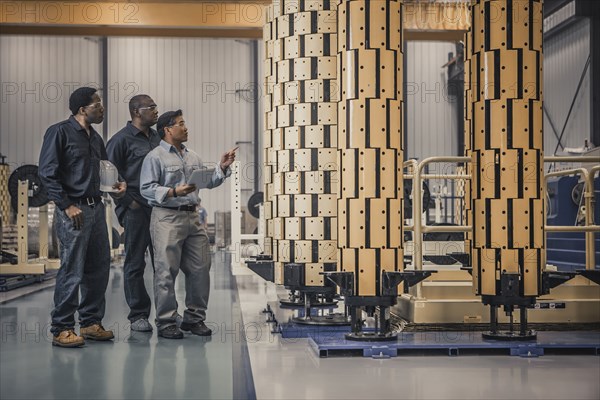 Workers looking at equipment in factory