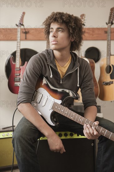 Mixed race teenager sitting with electric guitar