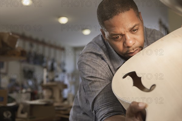 Native American man making guitar in workshop