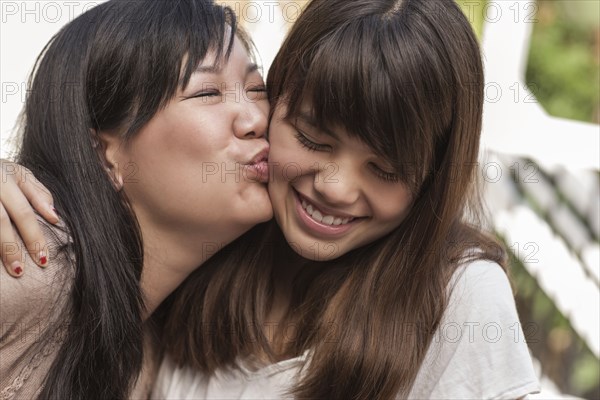 Mother kissing smiling daughter