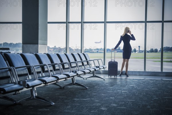 Caucasian businesswoman talking on cell phone in airport