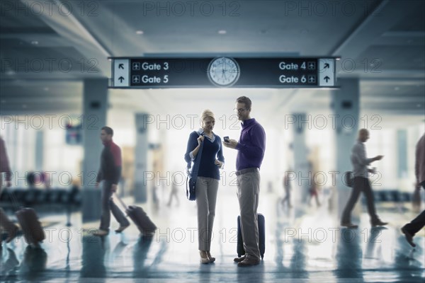 Caucasian couple looking at cell phone in airport