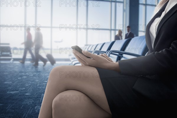 Caucasian businesswoman text messaging on cell phone in airport