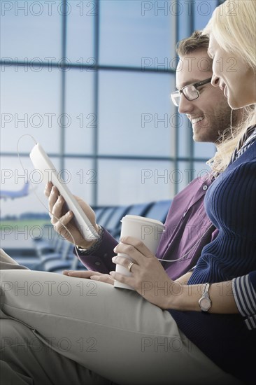 Caucasian couple using digital tablet in airport