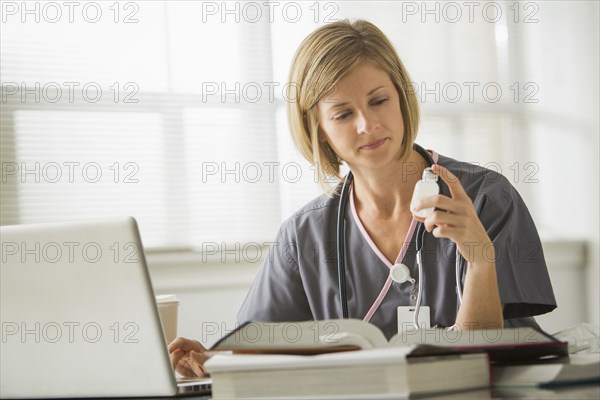 Caucasian nurse looking at medicine bottle