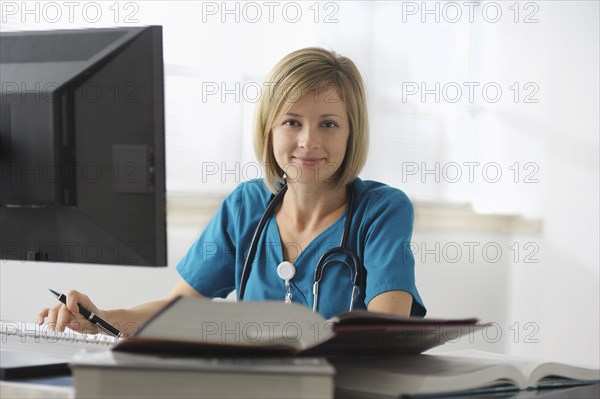 Caucasian surgeon reading books and using computer