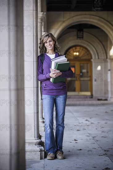 Caucasian student carrying books on campus