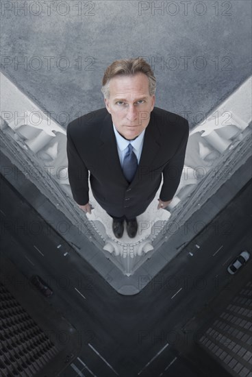 Caucasian businessman on skyscraper ledge