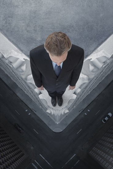 Caucasian businessman on skyscraper ledge