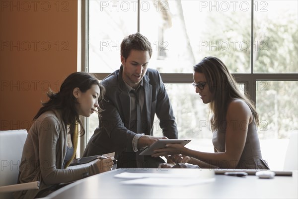 Business people using tablet computer in meeting