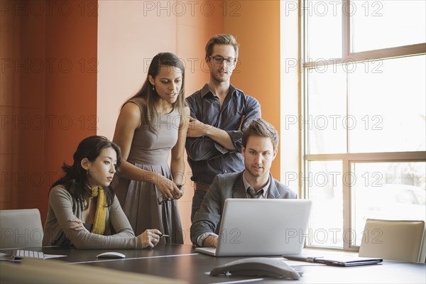 Businesspeople using laptop in meeting