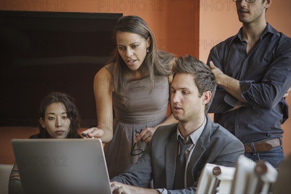 Businesspeople using laptop in meeting