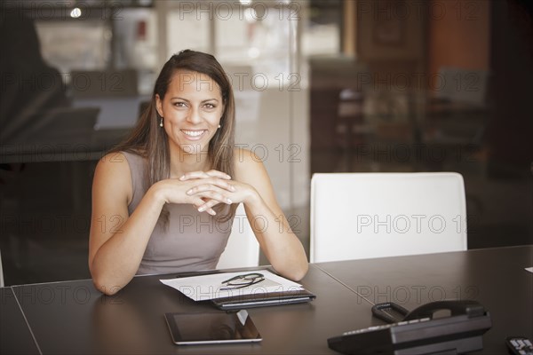 Mixed race businesswoman smiling at desk