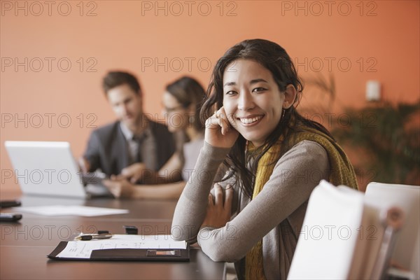 Mixed race businesswoman smiling at meeting table