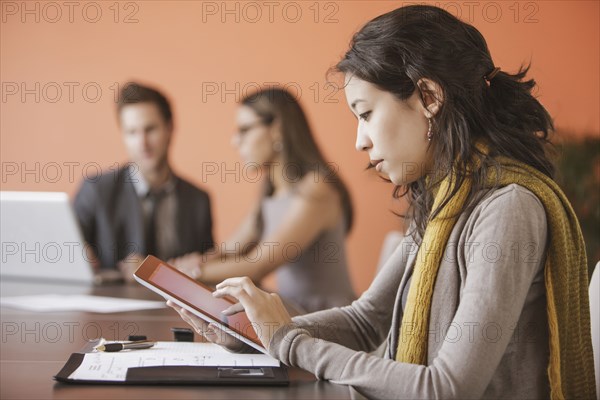 Mixed race businesswoman using tablet computer in meeting