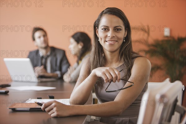 Mixed race businesswoman smiling at meeting table