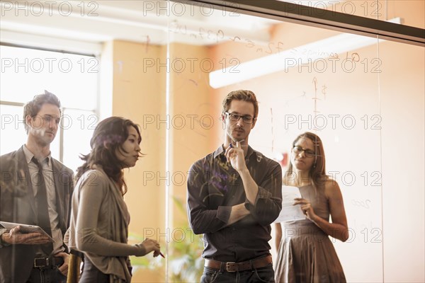 Business people writing on glass wall