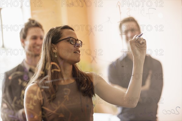 Mixed race businesswoman writing on glass wall