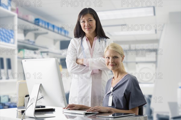 Doctor and nurse smiling at computer in hospital