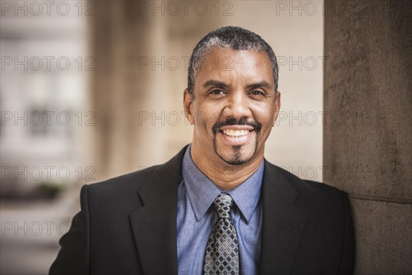 Mixed race businessman leaning on column