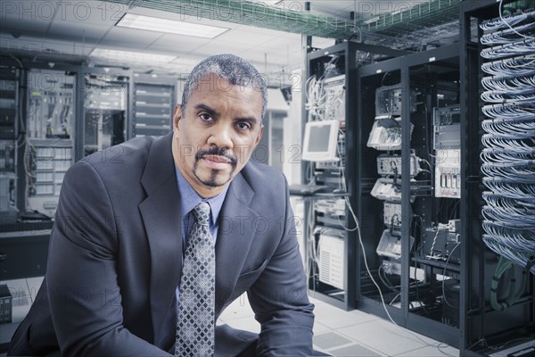 Mixed race businessman sitting in server room