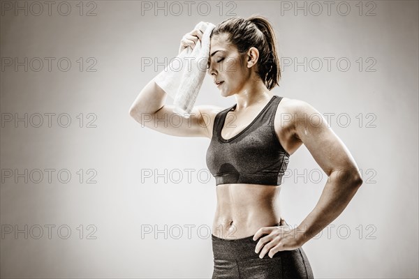 Caucasian woman wiping sweat from forehead