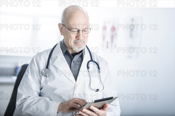 Caucasian doctor using tablet computer in office
