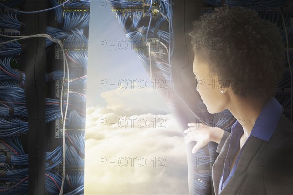 African American businesswoman pulling back curtain to clouds