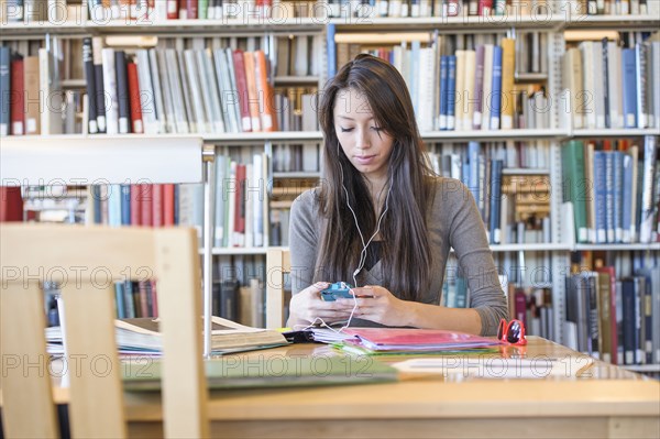 Student listening to earphones in library