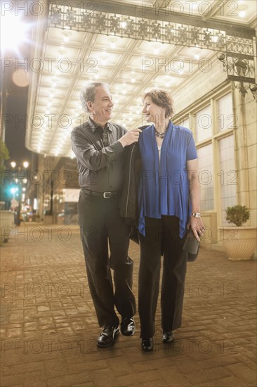 Caucasian couple walking on city street