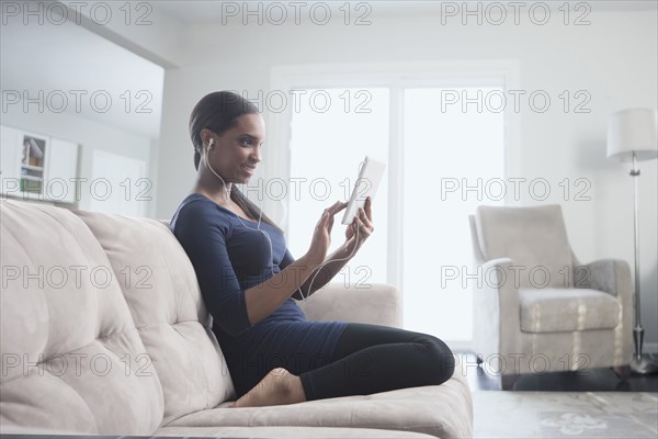 Black woman using digital tablet on sofa