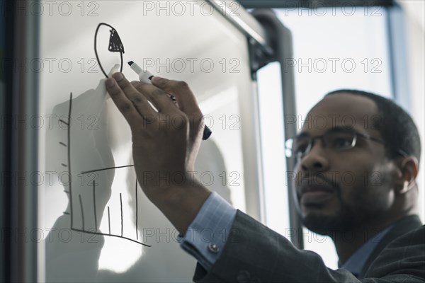 Businessman writing on whiteboard in office