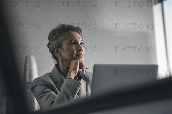 Mixed race businesswoman using laptop in office