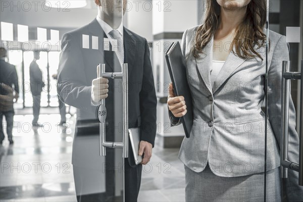 Businessman holding door open for female colleague