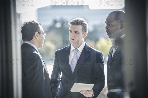 Businessmen using digital tablet outside office