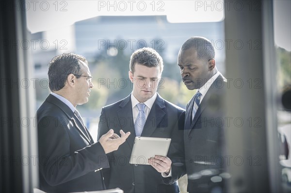 Businessmen using digital tablet outside office