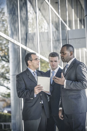 Businessmen using digital tablet outside office