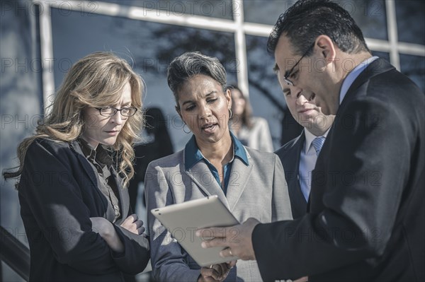 Business people using digital tablet outside office