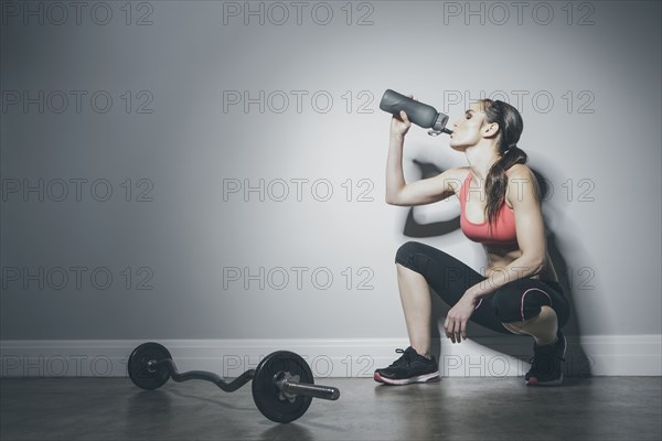 Caucasian woman in sportswear drinking from water bottle