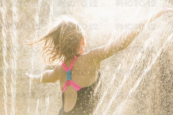 Girl standing in sprinkler