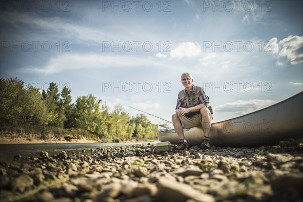 Older Caucasian man sitting in canoe on riverbed
