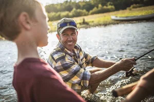 Caucasian father and son fishing in river