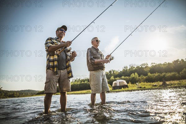 Caucasian father and son fishing in river