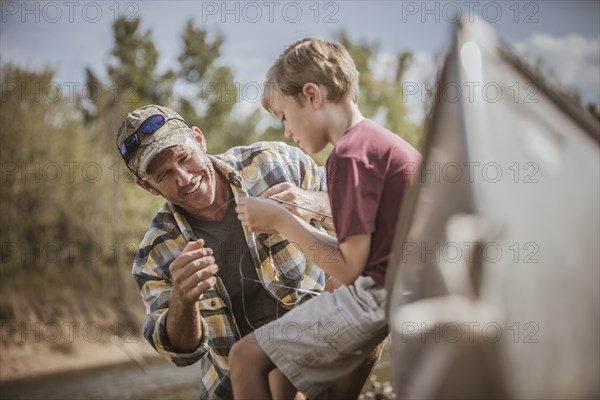 Caucasian father teaching son to tie fishing lures